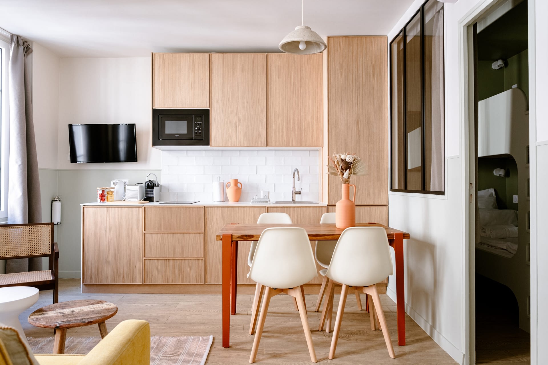 Modern kitchen and dining area in a Popincourt Paris apartment by The Babylon Stay, featuring warm wood finishes and contemporary design